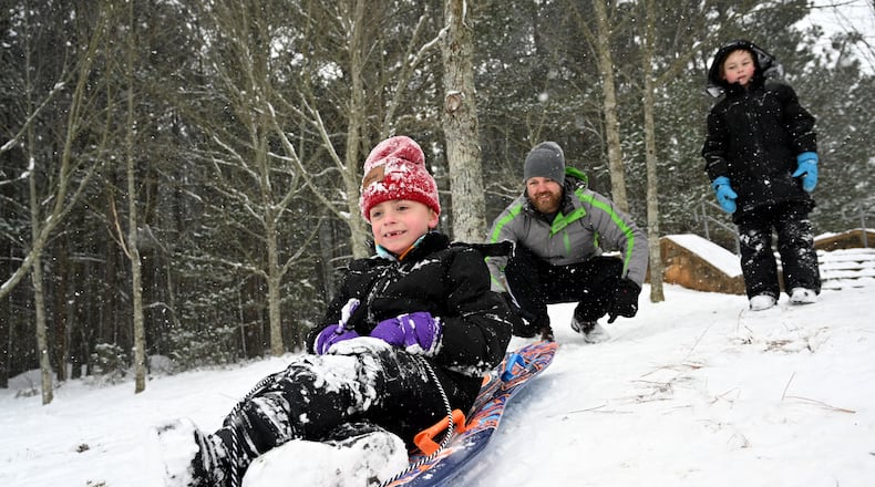 James Myers, 7, sleds down a hill Saturday as his father Lee Myers pushes him at Little Mulberry Park in Dacula, Georgia, north of Atlanta. (Hyosub Shin/AJC)
