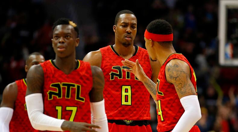 Atlanta Hawks center Dwight Howard (8) reacts with teammates guard Dennis Schroder (17) and forward Kent Bazemore (24) after his dunk in the second half of an NBA basketball game against the New York Knicks on Sunday, Jan. 29, 2017, in Atlanta. The Hawks won the game in the fourth overtime 142-139. (AP Photo/Todd Kirkland)