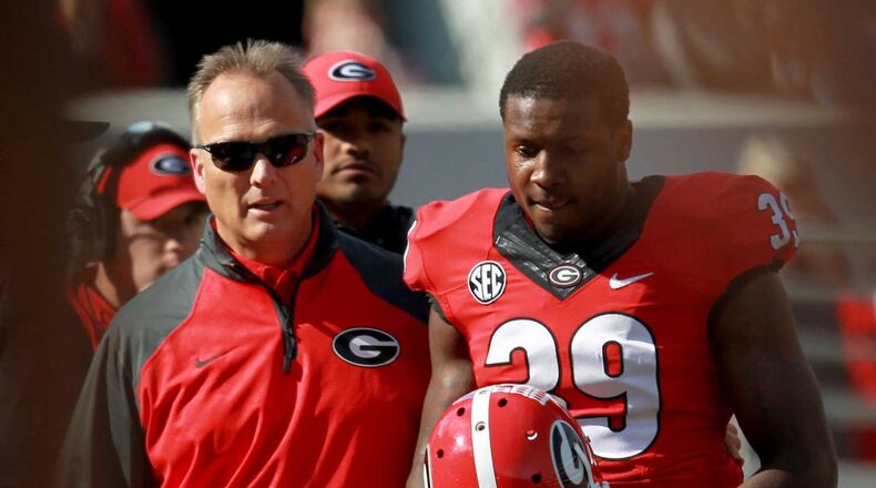 Georgia's Corey Moore (right) leaves the field after being ejected for a targeting penalty in 2013.