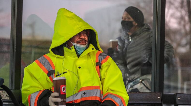 Jesus Garcia (left) and Deborah Simpson bundle up at the park-and-ride lot on the South Marietta Parkway loop in Marietta. Temperatures plunged into the 20s Friday morning as the coldest air of the season filtered into metro Atlanta.