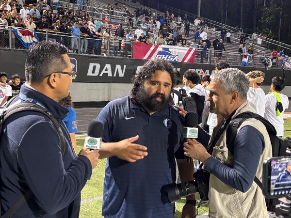 Meadowcreek coach Jose Rodriguez (center), being interviewed after the Mustangs won the Class 6A soccer championship on Thursday, says he was confident his team would prevail once the game came down to penalty kicks. (Stan Awtrey for the AJC)