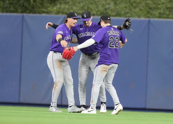 Colorado Rockies left fielder Jordan Beck, left, center fielder Brenton Doyle, center and right fielder Mickey Moniak (22) celebrate after the Rockies defeated the Miami Marlins in a baseball game, Tuesday, June 3, 2025, in Miami. (AP Photo/Lynne Sladky)