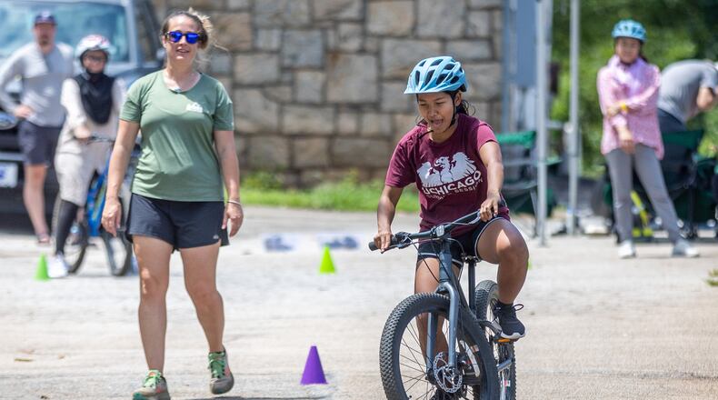 Instructor Ashley Clarkin watches Mang Bor Cin weave her bike through the cones during Mang Bor Cin's first bike riding lesson in Decatur Saturday. July 23, 2023. (Steve Schaefer/steve.schaefer@ajc.com)