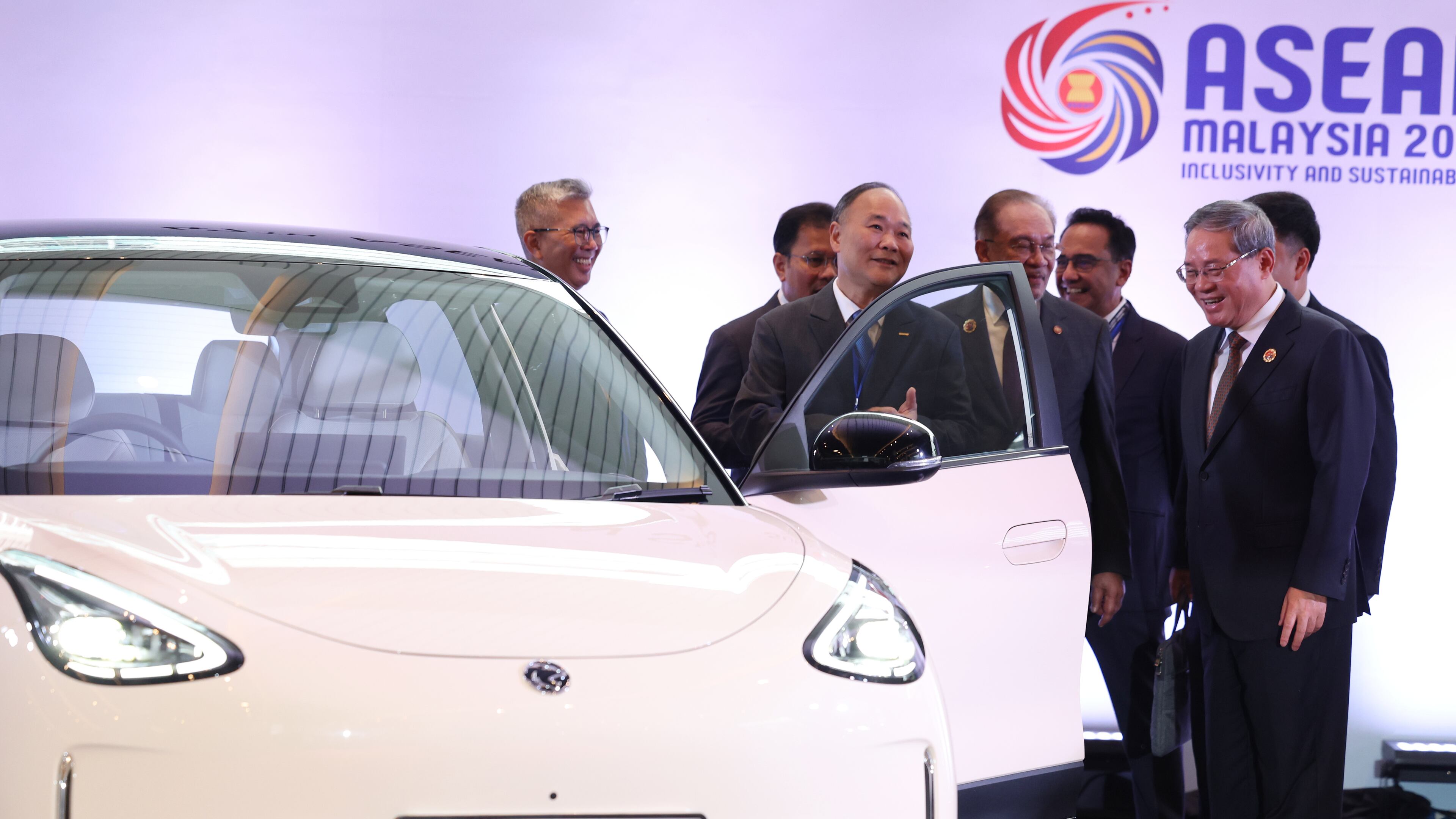 Chinese Premier Li Qiang, right, reacts as he, along with Malaysian Prime Minister Anwar Ibrahim, center, inspects a car produced by Malaysia's national automaker, Proton, in which China's Zhejiang Geely Holding Group holds a 49.9% stake, ahead of the signing ceremony for the ASEAN–China Free Trade Area 3.0 Upgrade and the ASEAN–China summit, held as part of the ASEAN summit in Kuala Lumpur, Malaysia Tuesday, Oct. 28, 2025. (Chalinee Thirasupa/Pool Photo via AP)
