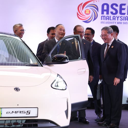 Chinese Premier Li Qiang, right, reacts as he, along with Malaysian Prime Minister Anwar Ibrahim, center, inspects a car produced by Malaysia's national automaker, Proton, in which China's Zhejiang Geely Holding Group holds a 49.9% stake, ahead of the signing ceremony for the ASEAN–China Free Trade Area 3.0 Upgrade and the ASEAN–China summit, held as part of the ASEAN summit in Kuala Lumpur, Malaysia Tuesday, Oct. 28, 2025. (Chalinee Thirasupa/Pool Photo via AP)