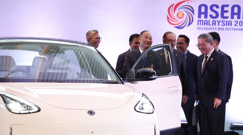 Chinese Premier Li Qiang, right, reacts as he, along with Malaysian Prime Minister Anwar Ibrahim, center, inspects a car produced by Malaysia's national automaker, Proton, in which China's Zhejiang Geely Holding Group holds a 49.9% stake, ahead of the signing ceremony for the ASEAN–China Free Trade Area 3.0 Upgrade and the ASEAN–China summit, held as part of the ASEAN summit in Kuala Lumpur, Malaysia Tuesday, Oct. 28, 2025. (Chalinee Thirasupa/Pool Photo via AP)