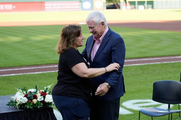 Cincinnati Reds owner Bob Castellini, right hugs Pete Rose's daughter Fawn Rose as they meet on the field for Pete Rose Night events before a baseball game between the Cincinnati Reds and the Chicago White Sox, Wednesday, May 14, 2025, in Cincinnati. (AP Photo/Carolyn Kaster)