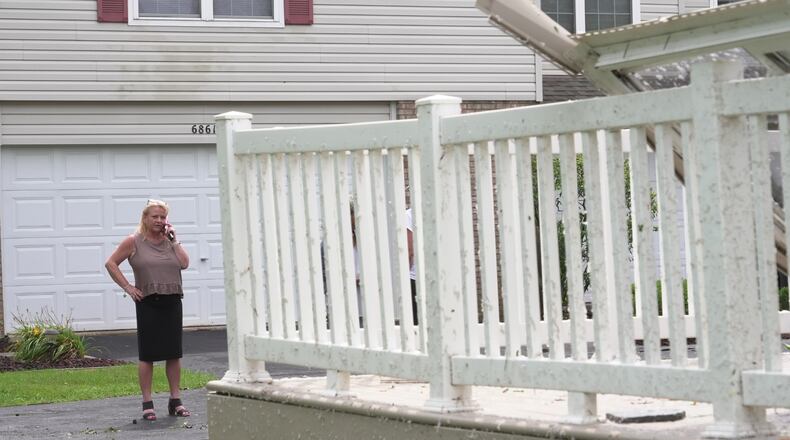 Kerry Hourigan speaks on the phone after reviewing damage a storm caused to her home in Tinley Park, Ill., Tuesday, Aug. 11, 2026. (AP Photo/Laura Bargfeld)