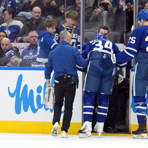 Toronto Maple Leafs Auston Matthews (34) is helped off the ice after being injured by Anaheim Ducks Radko Gudas during the second period of an NHL hockey game in Toronto, Thursday, March 12, 2026. (Nathan Denette/The Canadian Press via AP)