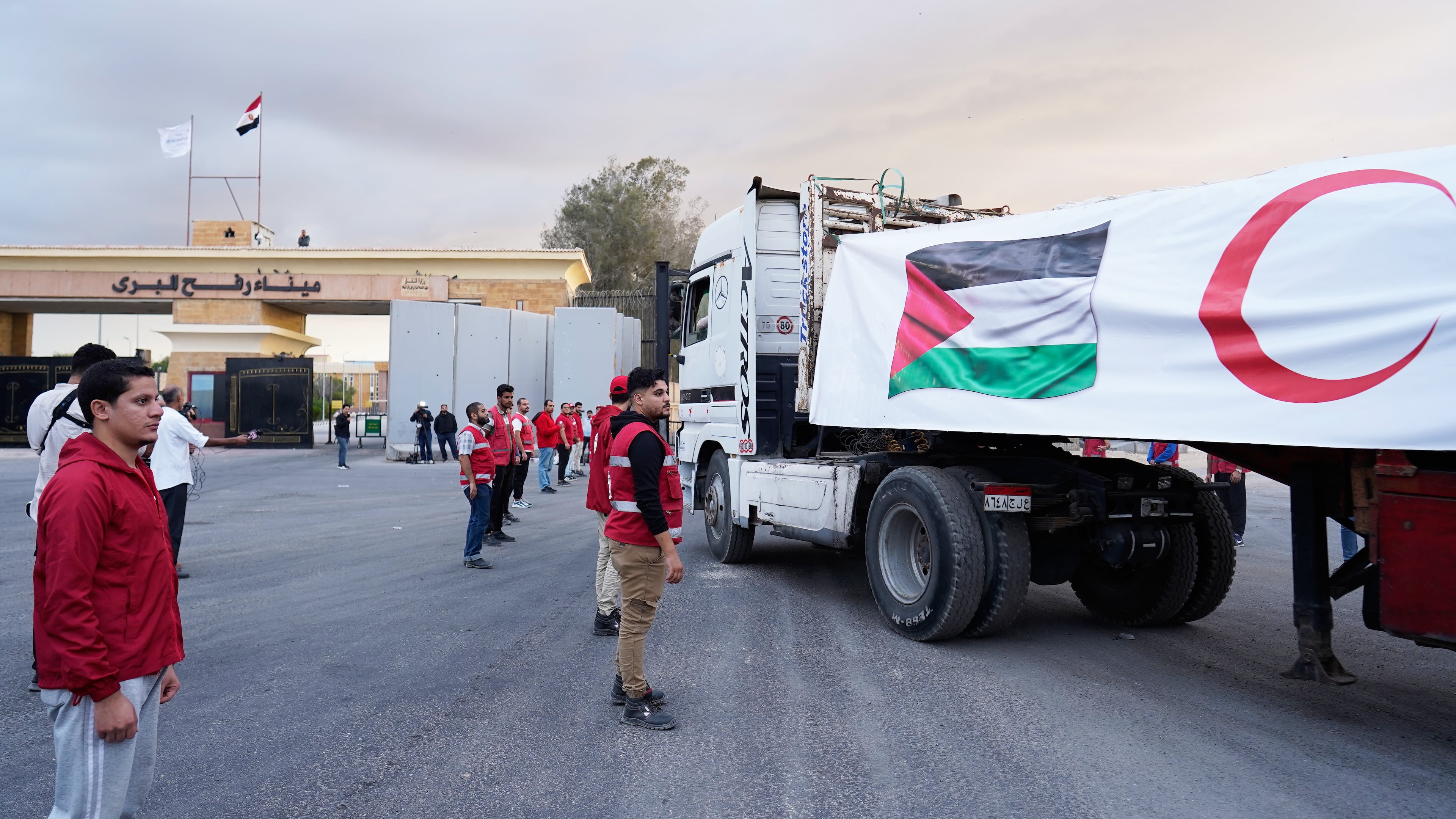 Egyptian Red Crecent members monitor trucks carrying humanitarian aid as they enter the Rafah crossing between Egypt and the Gaza Strip, following an agreement between Israel and Hamas on a ceasefire, Sunday, Oct. 12, 2025. (AP Photo/Mohamed Arafat)