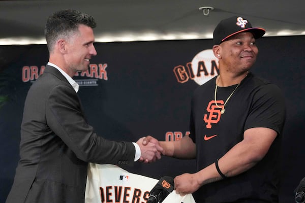 San Francisco Giants President of Baseball Operations Buster Posey, left, shakes hands with Rafael Devers during a news conference before a baseball game between the Giants and the Cleveland Guardians in San Francisco, Tuesday, June 17, 2025. (AP Photo/Jeff Chiu)