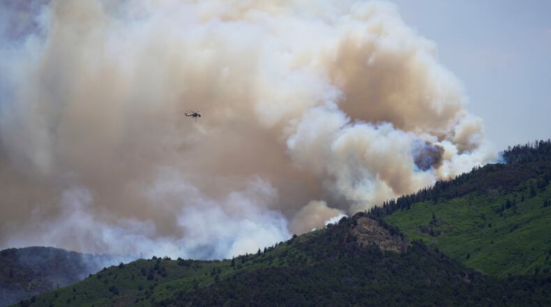 A helicopter flies near the Cottonwood Fire in Beaver, Utah, Tuesday, June 30, 2026. (AP Photo/Ty ONeil)