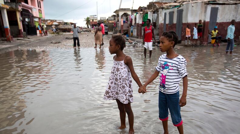 Girls hold hands as they help each other wade through a flooded street after the passing of Hurricane Matthew in Les Cayes, Haiti, Thursday, Oct. 6, 2016. Two days after the storm rampaged across the country's remote southwestern peninsula, authorities and aid workers still lack a clear picture of what they fear is the country's biggest disaster in years. (AP Photo/Dieu Nalio Chery)