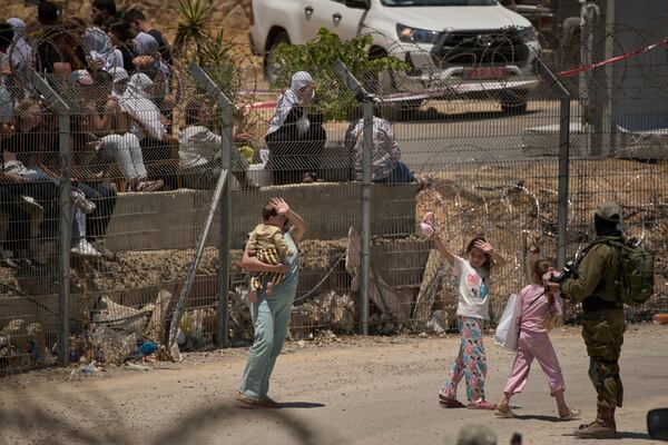 Members of a Syrian Druze family wave goodbye as they cross back into Syria at the Israeli-Syrian border, in the Israeli-controlled Golan Heights town of Majdal Shams, Thursday, July 17, 2025. (AP Photo/Leo Correa)