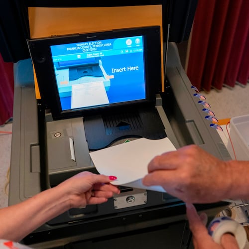 FILE - A polling judge, right, helps guide a voter's ballot into a voting machine during the Pennsylvania primary election, at Mont Alto United Methodist Church in Alto, Pa., on May 17, 2022. (AP Photo/Carolyn Kaster, File)