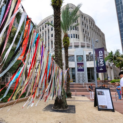 A person reads about the prayer ribbons honoring those killed in the 2016 Pulse nightclub shooting at Orlando City Hall, in Orlando, Fla., Tuesday, June 9, 2026. (Joe Burbank/Orlando Sentinel via AP)