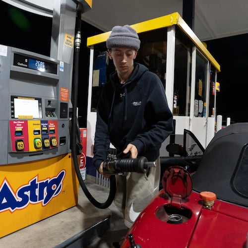 Luciano V. replaces the fuel nozzel after filling the tank of their 1999 Mazda Miata at an Astro gas station on Wednesday, April 29, 2026, in Portland, Ore. (AP Photo/Jenny Kane)