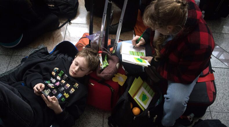 Heidi Harrington (right) and her son Dillon wait to check in for their flight to New York in a dark terminal at Hartsfield-Jackson International Airport on Sunday, Dec. 17, 2017. A power outage that lasted for hours brought the airport to a standstill. STEVE SCHAEFER / SPECIAL TO THE AJC