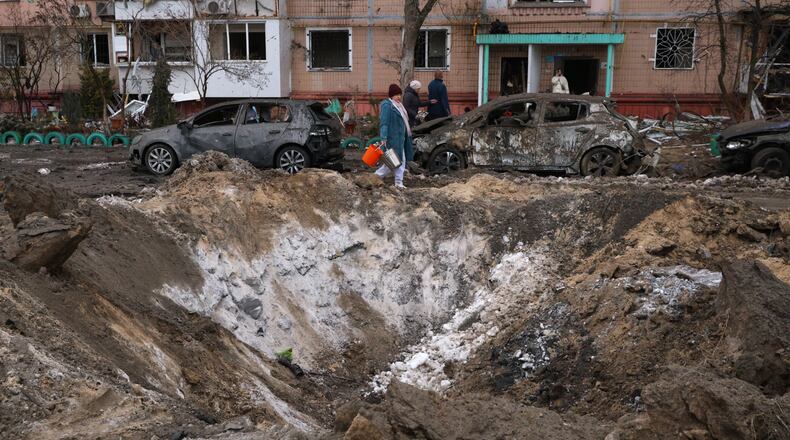 People pass a crater and damaged cars near an apartment building after a Russian attack in Zaporizhzhia, Ukraine, Wednesday, Jan. 28, 2026. (AP Photo/Kateryna Klochko)
