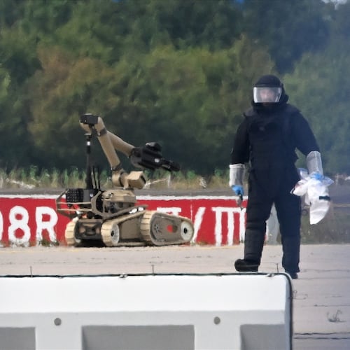 A forensic technician works alongside a bomb-disposal robot near a Ukrainian aircraft at Leipzig/Halle Airport, where a drone with an explosive device was found and a detonator was removed from the object, in Schkeuditz, Germany, Wednesday Aug. 5, 2026. (Hendrik Schmidt/dpa via AP)