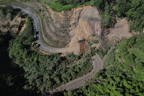 A backhoe works to clear a road blocked by a landslide in Palin, Guatemala, after dozens of earthquakes and aftershocks were recorded in a matter of hours. (AP Photo/Moises Castillo)