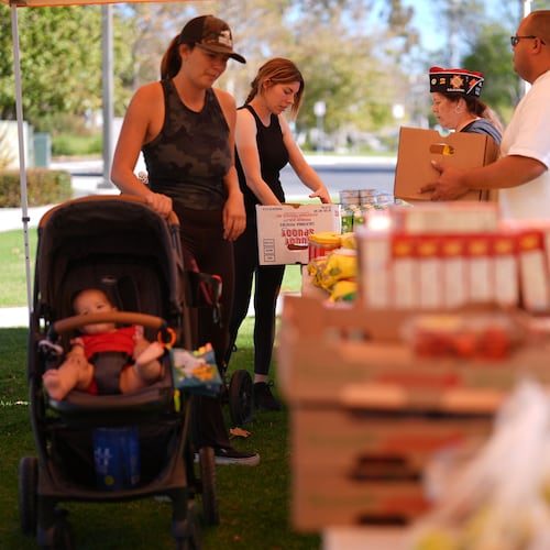 Elana Peck, back, who's husband is active duty Marine, stands on line to receive food during a Feeding San Diego food distribution for military families affected by the federal shutdown Friday, Nov. 7, 2025, in Oceanside, Calif. (AP Photo/Gregory Bull)