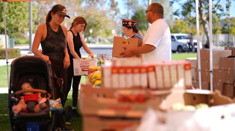 Elana Peck, back, who's husband is active duty Marine, stands on line to receive food during a Feeding San Diego food distribution for military families affected by the federal shutdown Friday, Nov. 7, 2025, in Oceanside, Calif. (AP Photo/Gregory Bull)