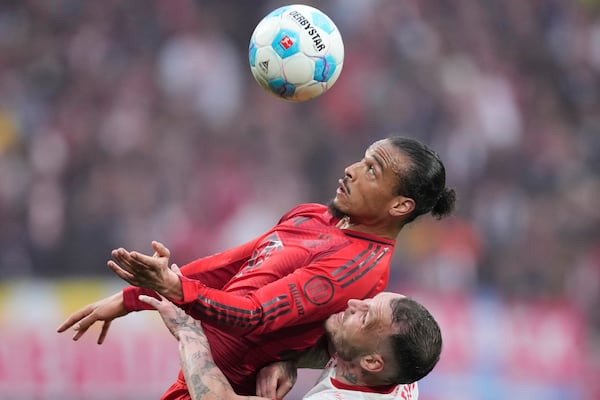 Bayern's Leroy Sane challenges for the ball with Leipzig's David Raum, bottom, during the German Bundesliga soccer match between RB Leipzig and FC Bayern Munich at the Red Bull Arena in Leipzig, Germany, Saturday, May 3, 2025. (AP Photo/Ebrahim Noroozi)
