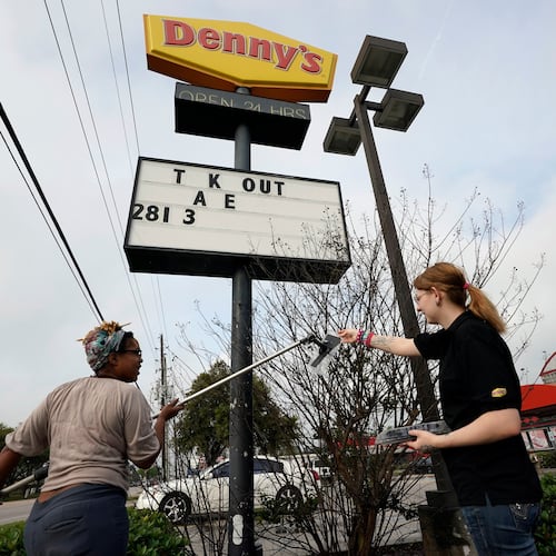FILE - Ieisha Dede, left, and Cali Malatek put up a takeout sign outside a Denny's restaurant, March 17, 2020, in Spring, Texas. (AP Photo/David J. Phillip, File)