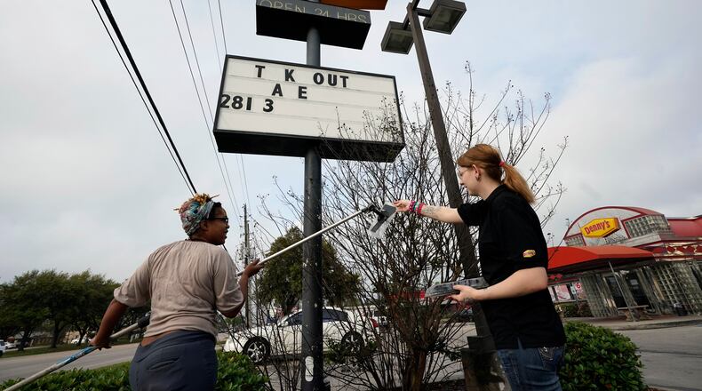 FILE - Ieisha Dede, left, and Cali Malatek put up a takeout sign outside a Denny's restaurant, March 17, 2020, in Spring, Texas. (AP Photo/David J. Phillip, File)