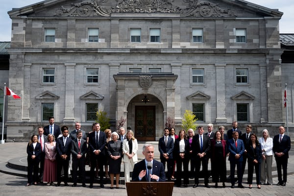 Members of Canada's Prime Minister Mark Carney's newly sworn in cabinet look on as Carney, center, speaks to reporters following a swearing-in ceremony at Rideau Hall in Ottawa, Ontario, Tuesday, May 13, 2025. (Spencer Colby/The Canadian Press via AP)