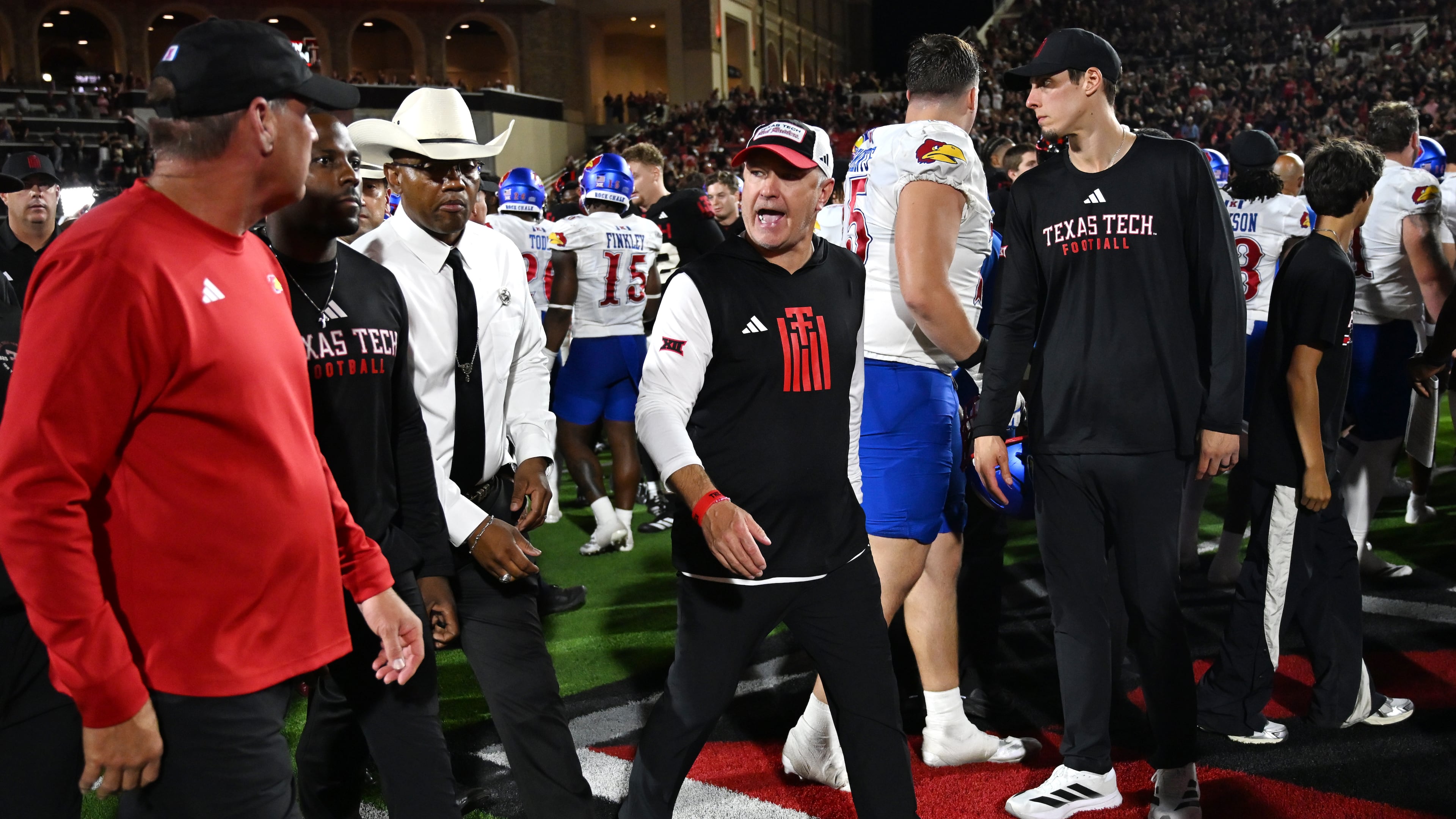 Texas Tech head coach Joey McGuire, center, speaks to Kansas head coach Lance Leipold, left, after the end of the NCAA college football game, Saturday, Oct. 11, 2025, in Lubbock, Texas. (AP Photo/Annie Rice)