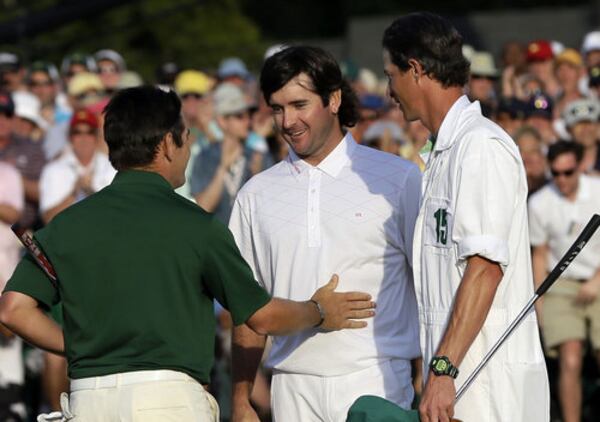 Louis Oosthuizen, left, of South Africa, congratulates Bubba Watson on the 18th green following their fourth round of the Masters golf tournament in Augusta, Ga. At right is Watson's caddie, Ted Scott.