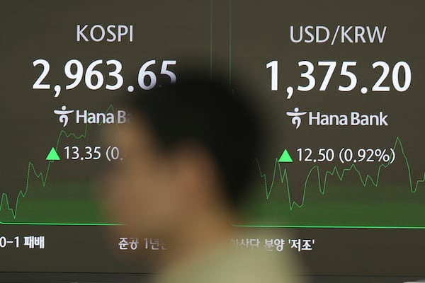 A dealer walks past near the screens showing the Korea Composite Stock Price Index (KOSPI), left, and the foreign exchange rate between U.S. dollar and South Korean won at a dealing room of Hana Bank in Seoul, South Korea, Wednesday, June 18, 2025. (AP Photo/Lee Jin-man)