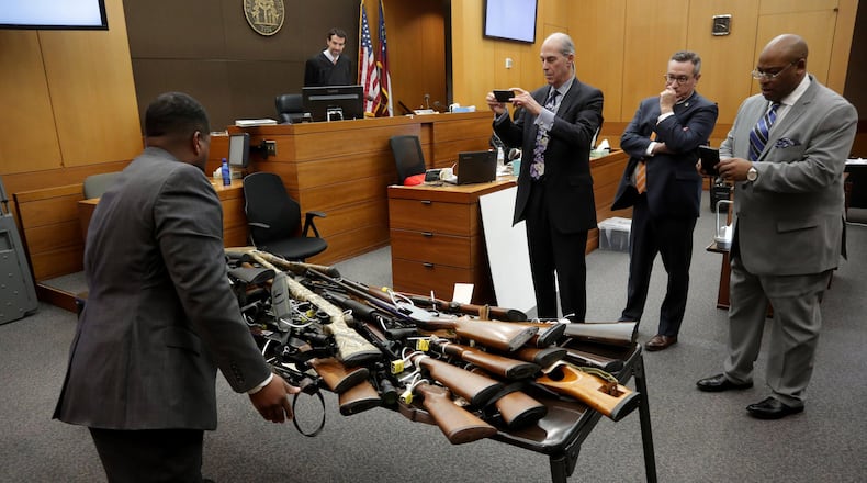 Defense attorneys Bruce Harvey at left, and Fulton County Chief Assistant District Attorney Clint Rucker, far right, take photos of a table full of Tex McIver's guns.
STEVE SCHAEFER / SPECIAL TO THE AJC