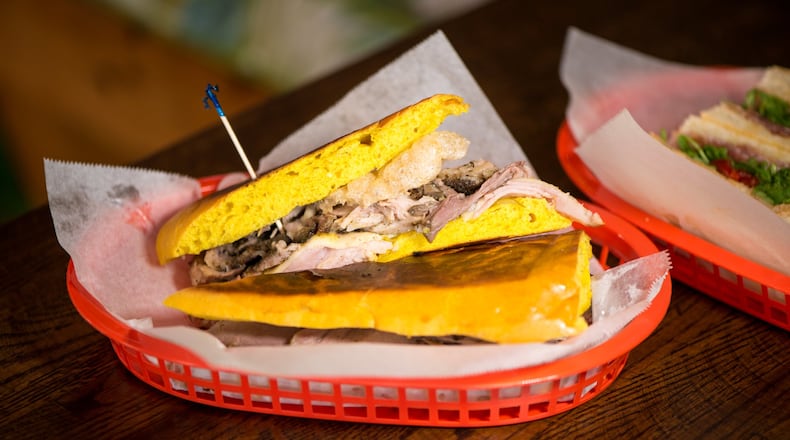 El Super Pan Media Noche sandwich with pan de huevo, Cuban adobo roasted pork, ham, chicharron, Swiss cheese, pickles, yellow mustard. Photo credit- Mia Yakel.