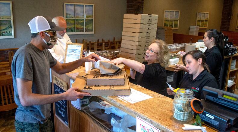 Steve Pifer (L) picks up an order of pizza at Fini’s Pizzeria on a Friday night in Lawrenceville. STEVE SCHAEFER / SPECIAL TO THE AJC
