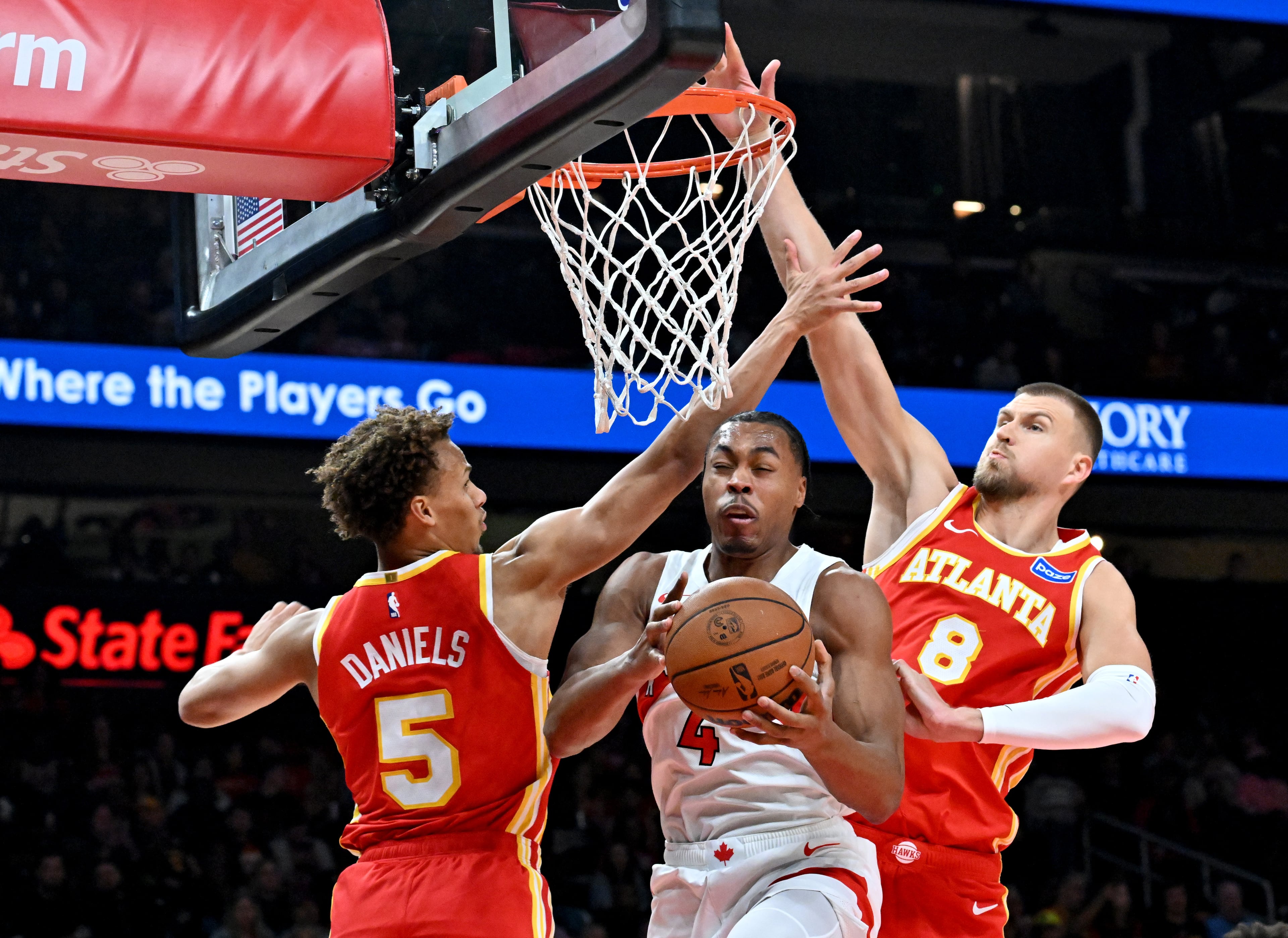 Toronto Raptors forward/guard Scottie Barnes (4) gets a double coverage by Atlanta Hawks guard Dyson Daniels (5) and Atlanta Hawks forward/center Kristaps Porziņģis (8) during the first half in the home opener at State Farm Arena, Thursday, October 22, 2025, in Atlanta. (Hyosub Shin / AJC)