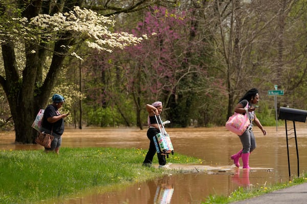 Marquetta Wheeler, right, with Samaria Williams and Jemaria Shaw walk through flood waters as they leave their home on Marietta Drive in Hopkinsville, Ky., Friday, April 4, 2025. (AP Photo/George Walker IV)