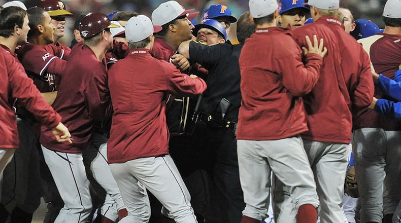 Heisman Trophy winner Jameis Winston, a pitcher on the Florida State baseball team, is held back a sheriff's deputy as the team engaged in a bench-clearing dustup with cross-state rival Florida Gators.