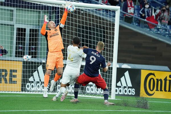 Atlanta United goalkeeper Brad Guzan (left) blocks shot on goal as defender Anton Walkes (4) holds off the attack of New England forward Adam Buska (9) during their match Saturday, May 1, 2021, in Foxborough, Mass. (MLS)