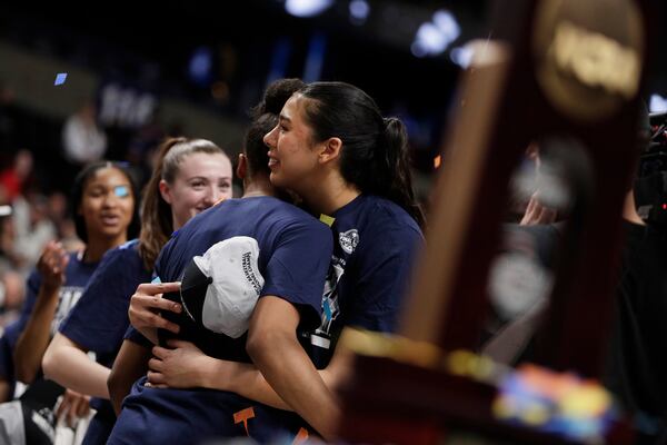 UConn players including Jana El Alfy, center, celebrate near the trophy after their win against Southern California in the Elite Eight of the NCAA college basketball tournament, Monday, March 31, 2025, in Spokane, Wash. (AP Photo/Young Kwak)
