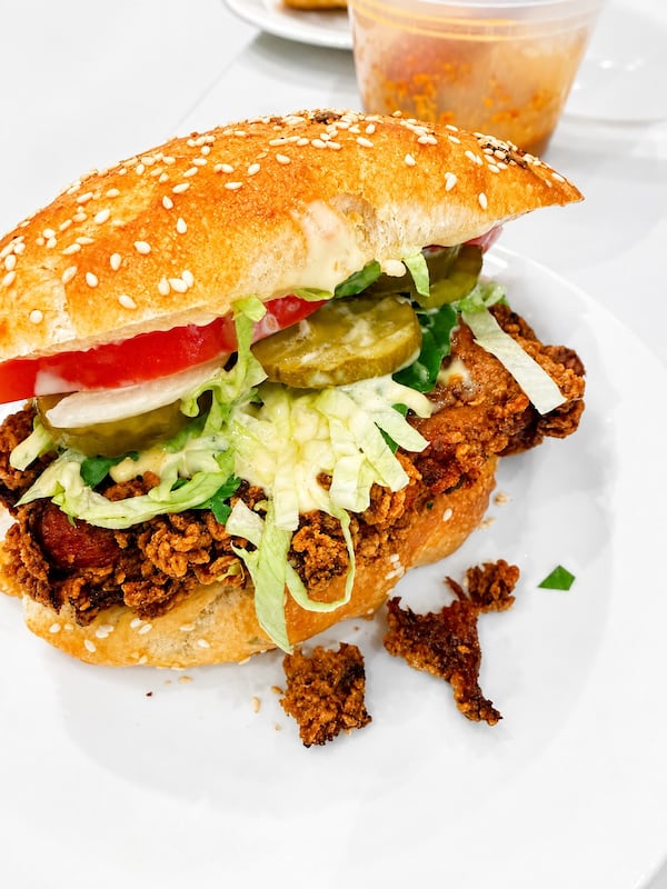 Sandwich with seasoned meat, lettuce, tomato, onion and pickles on a sesame seed bun.