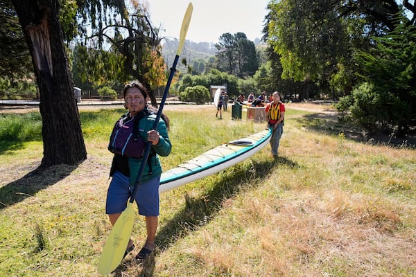 From left, Juan Bay, president of the Waorani people of Ecuador, and Isabella Zizi carry a kayak to the beach before entering the San Francisco Bay, Thursday, June 19, 2025, in Richmond, Calif. (AP Photo/Godofredo A. Vásquez)