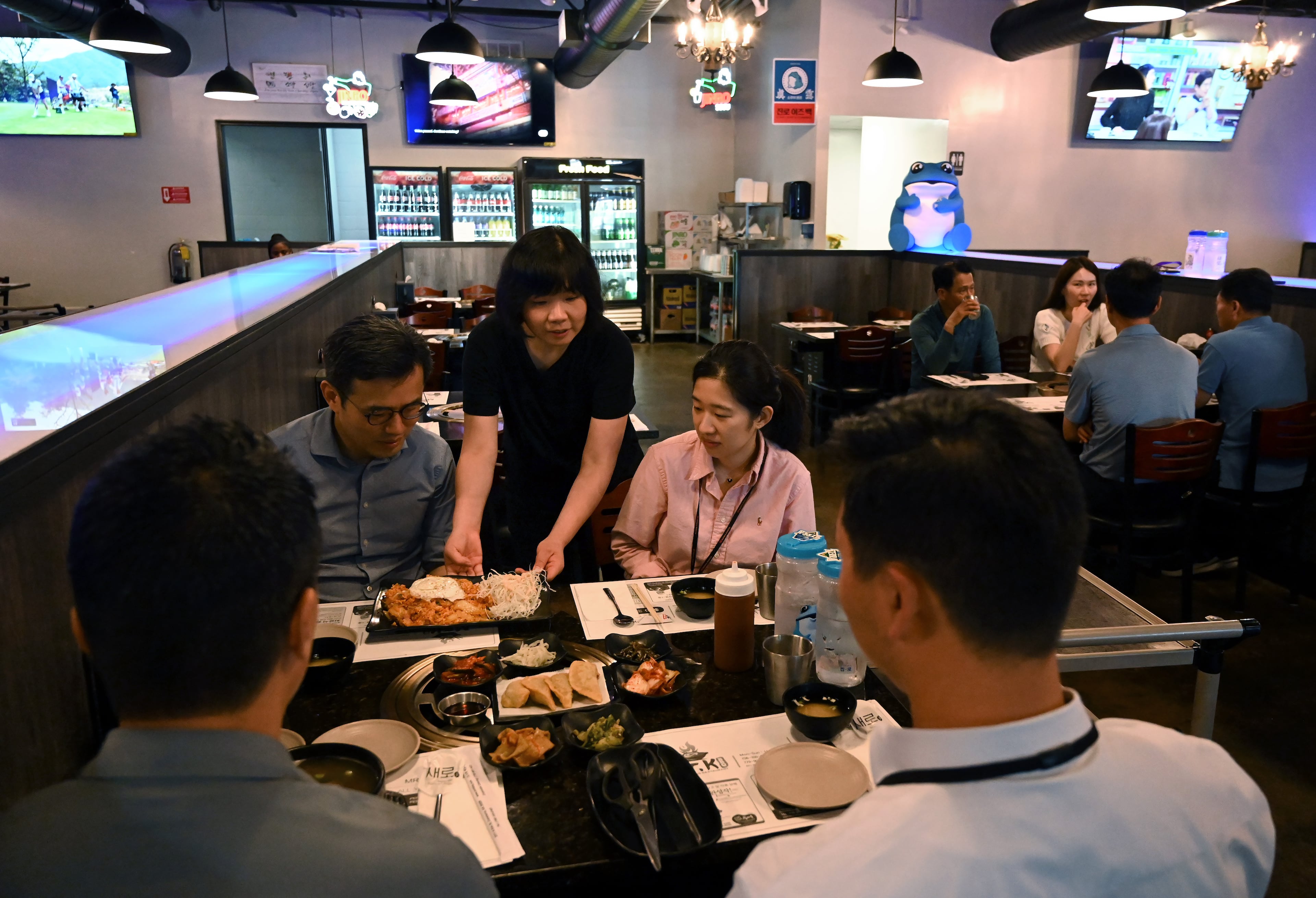 Jamie Ahn (standing) serves lunch-goers at Mr. K Korean BBQ, one of newer restaurants near downtown Commerce, Tuesday. SK has spurred new business such as Mr. K BBQ. (Hyosub Shin/AJC)