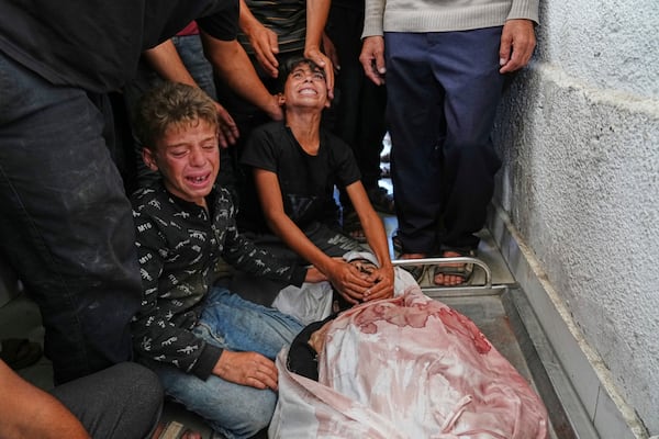 Palestinians children mourn over the body of their father, Mohammed Ghaben, who was killed while heading to an aid distribution hub, at the morgue of the Shifa Hospital in Gaza City, Wednesday, June 18, 2025. (AP Photo/Jehad Alshrafi)