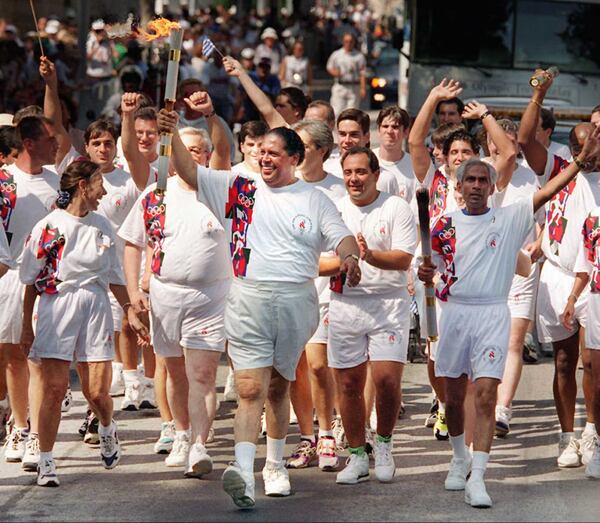 Former Atlanta Mayor Maynard Jackson carries the torch up Washington Street on its way to City Hall on Friday, July 19, for a final ceremony before heading to the Olympic stadium for the opening ceremony of the 1996 Summer Olympic Games later in the evening. (Greg Lovett/Cox News Service 1996)