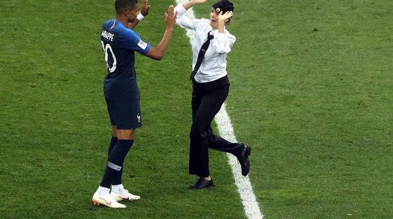 A woman who invaded the pitch approaches France's Kylian Mbappe during the final match between France and Croatia at Sunday's World Cup final.