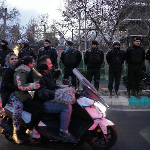 Policemen protect the British Embassy during a protest by hardline supporters of the Iranian government, as people ride on their motorbike in Tehran, Iran, Wednesday, Jan. 14, 2026. (AP Photo/Vahid Salemi)