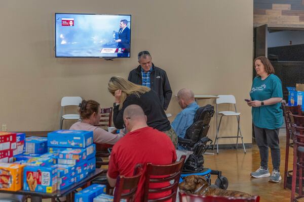 Families evacuated from wildfires near Norman, Okla. talk and watch the latest news information on tv at CrossPoint Church in Norman on Friday, March 14, 2025. (AP Photo/Alonzo Adams)